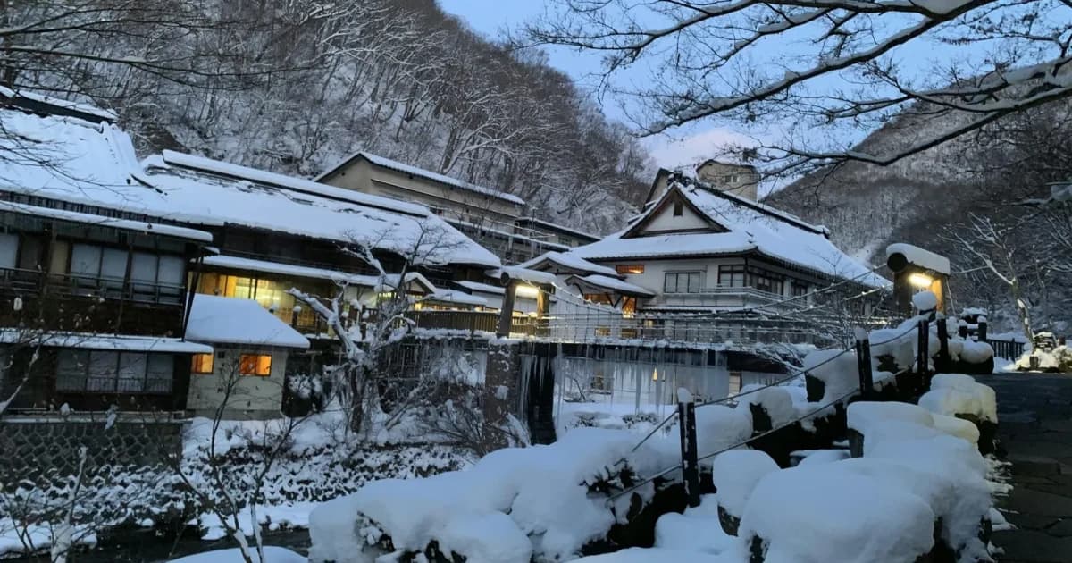 雪に包まれた山あいの温泉旅館の夕暮れ